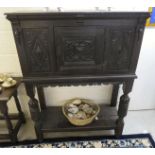 A late Victorian stained oak court cupboard with a central panelled, carved door,