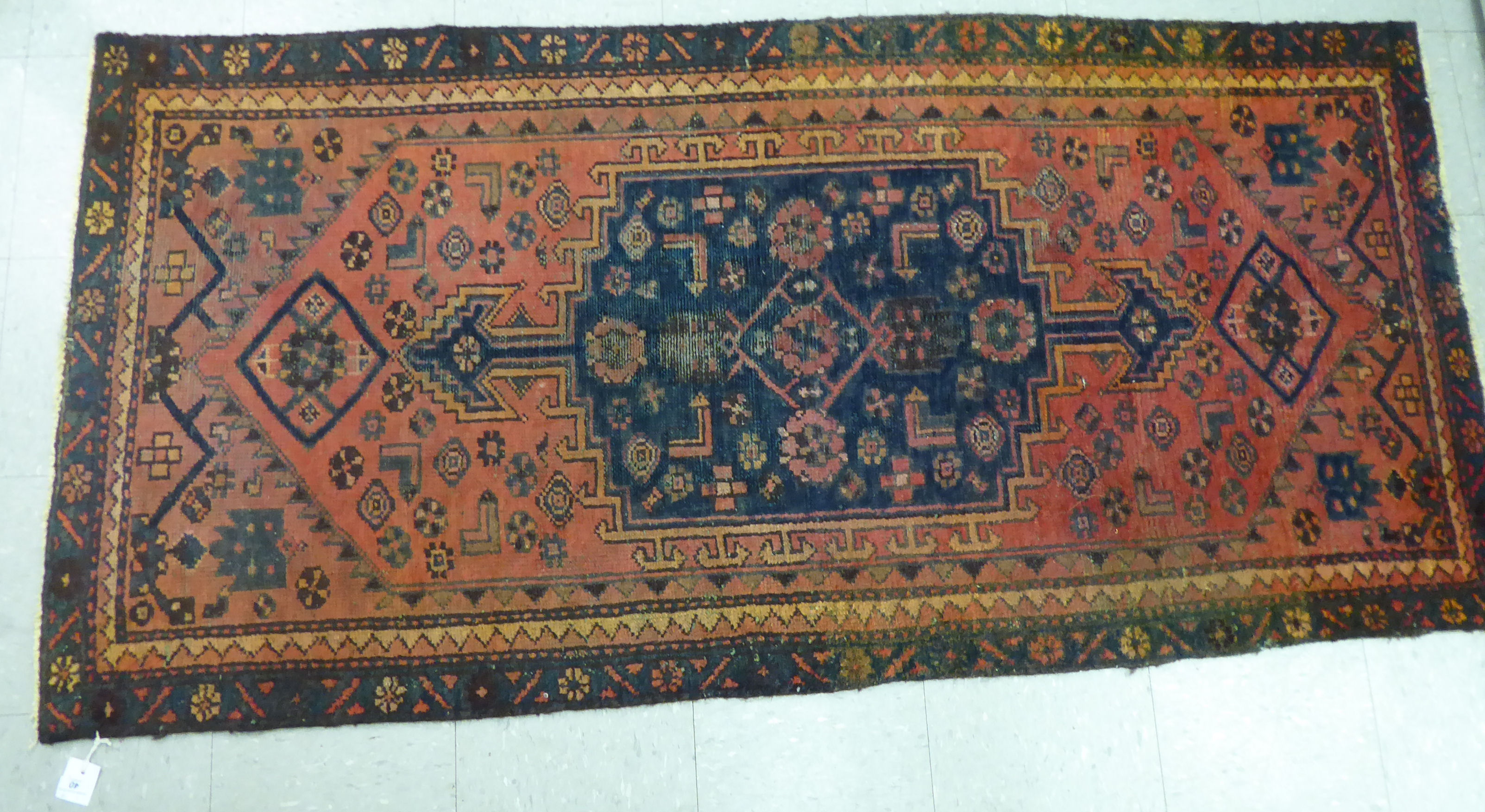 A Caucasian rug, decorated with a central medallion and stylised designs,