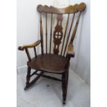 An early 20thC stained beech and elm framed rocking chair with a spindle turned back,