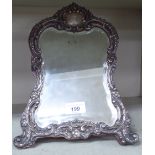 An Edwardian silver mounted frame with a shaped, bevelled mirrored plate,