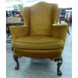 A 1930s old gold coloured dralon upholstered wingback armchair,