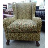 An early 20thC wingback armchair, later upholstered in floral patterned fabric,