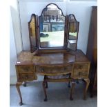 An early/mid 20thC bow front five drawer kneehole dressing chest, surmounted by a triptych mirror,