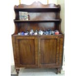A late Regency inspired mahogany cabinet bookcase with a two tier waterfall front superstructure,