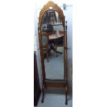 A mid 20thC walnut framed cheval mirror with an arched plate, pivoting on square, tapered horns,