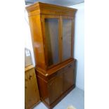 A modern yewwood finished cabinet bookcase, the upper part enclosed by a pair of line-cut,