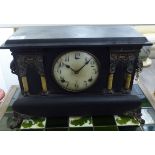 A late Victorian black painted wooden cased mantel clock of architectural form;