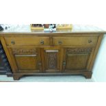 A 1930s stained oak sideboard with two in-line drawers, over a pair of panelled,