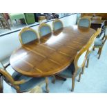 A modern Regency style yewwood finished dining table, the oval top with an additional leaf,