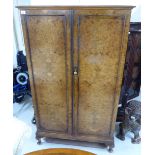An early/mid 20thC burr walnut finished wardrobe with a pair of doors, raised on stubby,
