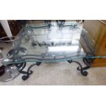 A modern black painted wrought iron coffee table, the glass top with a serpentine edge,