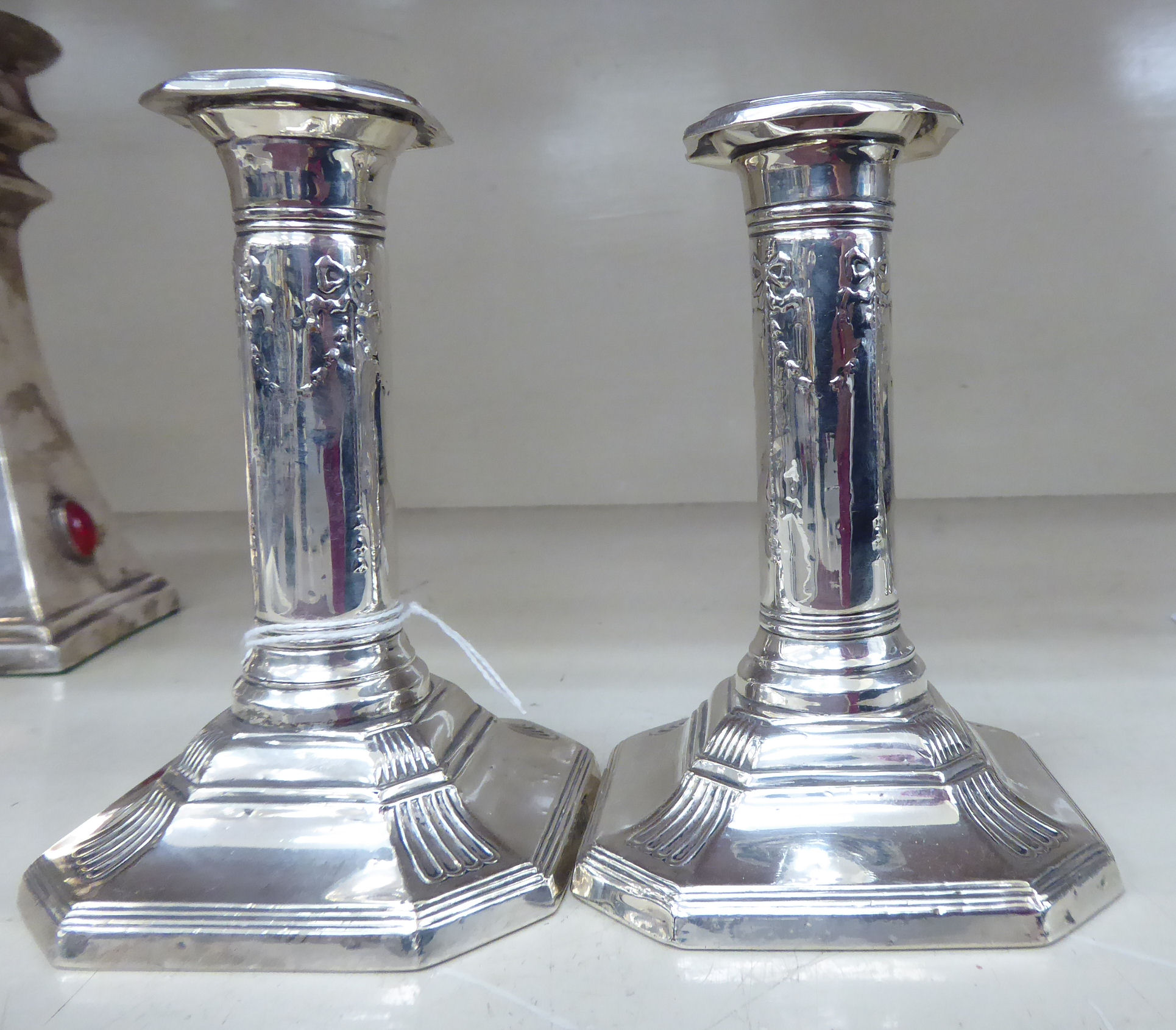 A pair of loaded silver candlesticks, each with bow and ribbon ornament,