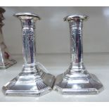 A pair of loaded silver candlesticks, each with bow and ribbon ornament,