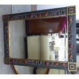 A modern mirror, the bevelled plate set in a wide, green painted and gilded frame,