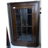 An early 20thC oak corner cupboard with a glazed door,