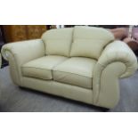 A modern cream coloured hide two person settee with showwood framed arms and cream coloured crushed