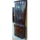 A modern mahogany corner cupboard with a glazed top, over a single door,