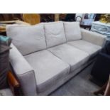 A modern cream coloured suede upholstered, low level backed, three person settee,