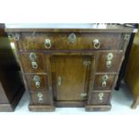 An early 19thC child's crossbanded and walnut twin pedestal seven drawer desk,