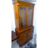 A modern yewwood finished cabinet bookcase, the upper part enclosed by a pair of line-cut,