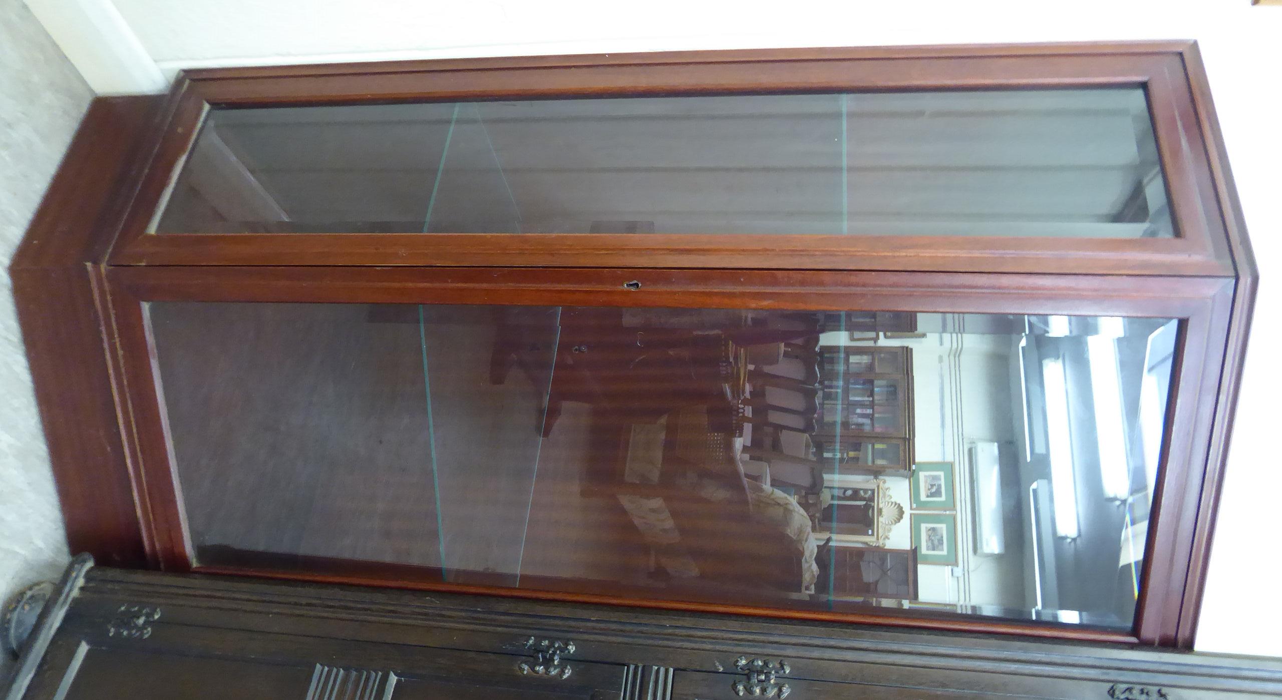 A modern mahogany corner unit with a bevelled glass panelled front, enclosing two shelves,