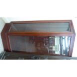 A modern mahogany corner unit with a bevelled glass panelled front, enclosing two shelves,