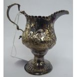 A George III silver pear shaped pedestal cream jug with embossed floral and spot-hammered dot