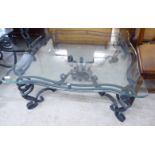 A modern black painted wrought iron coffee table, the glass top with a serpentine outlined edge,