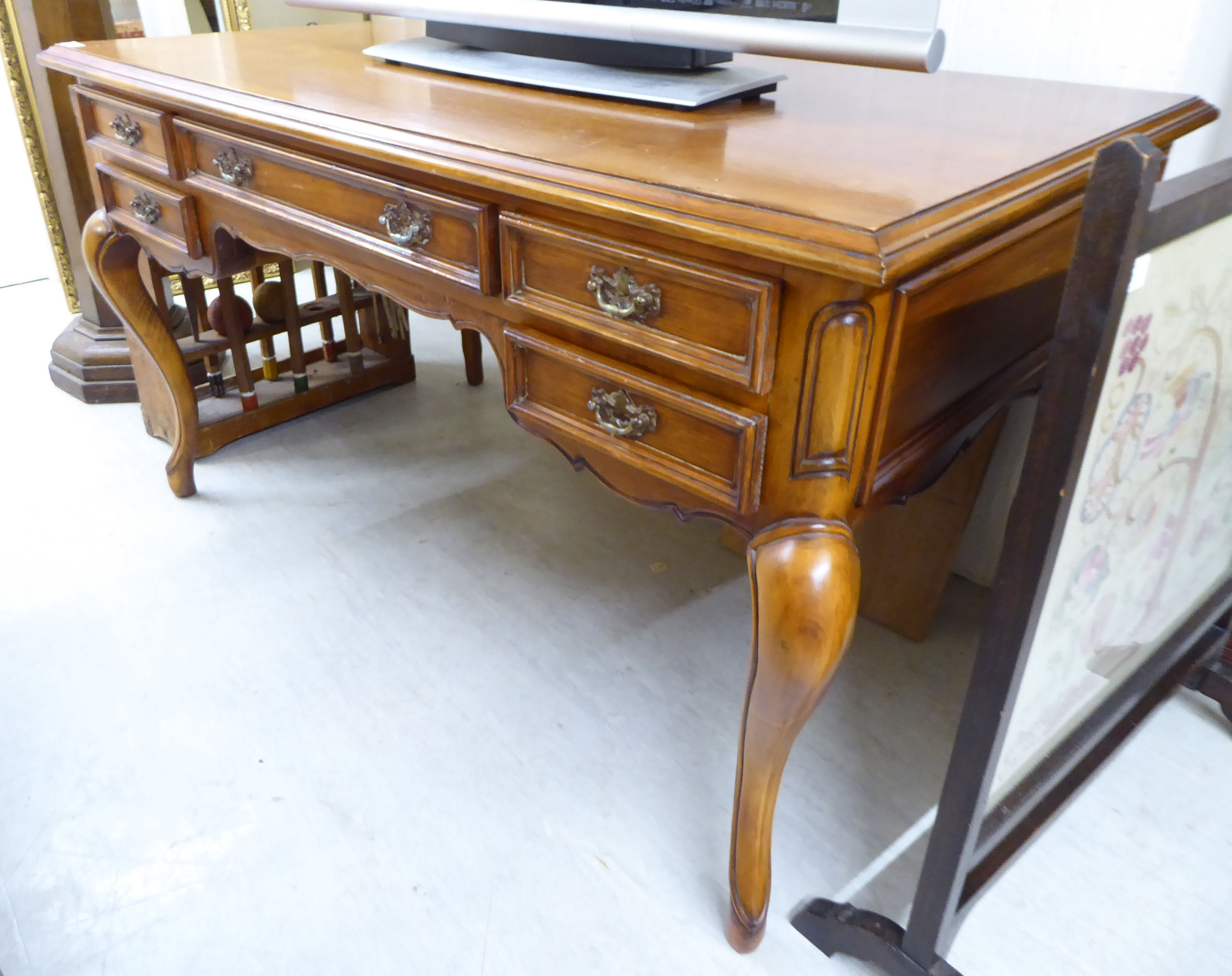 A modern Louis XV inspired mahogany finished kneehole desk with five graduated drawers,