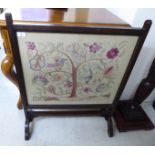 A 1920s oak framed firescreen, set with a pictorial needleworked panel,