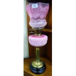 A late Victorian oil lamp with moulded pink glass reservoir, a brass burner fitting and stem,