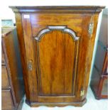 A George III stained oak quadrant corner cabinet with a pair of doors,