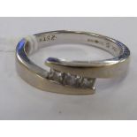 An 18ct white gold three stone diamond set crossover ring 11