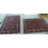 A pair of Persian rugs, decorated with stylised flora, bordered by additional foliage,