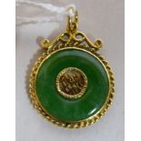 A Chinese gold coloured metal and jade set disc pendant with a twist wire border and suspension