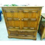 An Ercol light elm television cabinet, comprising two panelled doors and a fall flap,