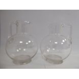 A pair of early 20thC clear, blown glass spherical jugs with wide, straight necks and drawn,