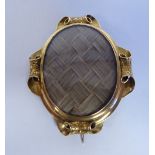 An early Victorian 9ct gold oval mourning brooch, set with plaited hair, behind glass,