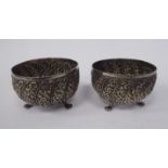 A pair of late 19thC Asian silver coloured metal bulbous bowls, elevated on three claw feet,