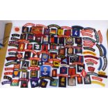 A collection of military and related printed end embroidered uniform badges,