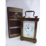 A modern lacquered brass cased carriage clock, having bevelled glass panels, reed cast corners,
