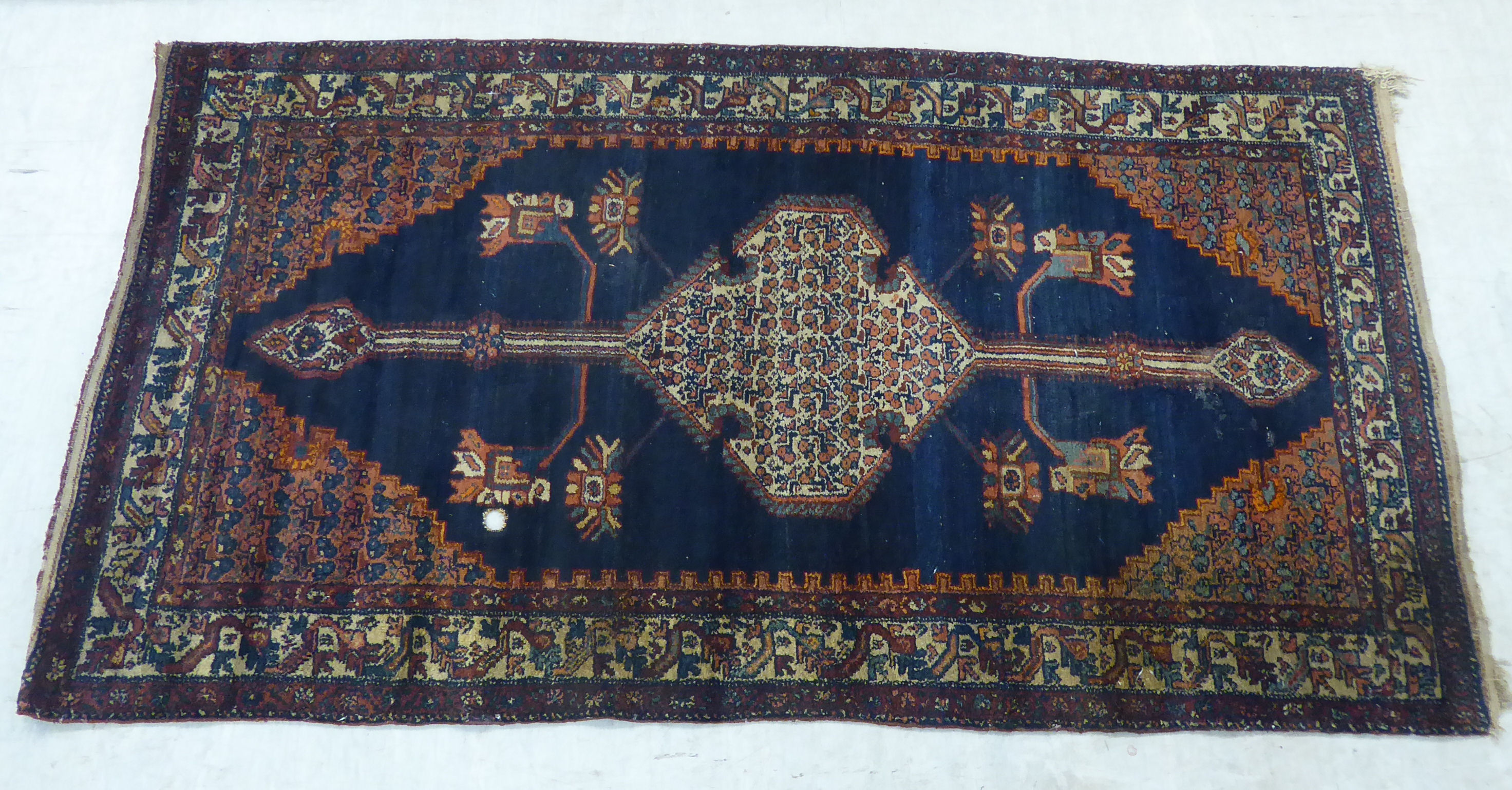A Persian rug, decorated with a central medallion and four corners of stylised designs,