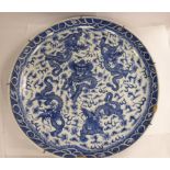 An early 19thC Chinese porcelain shallow, footed dish, decorated in blue and white with dragons,