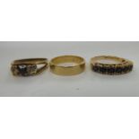 A 9ct gold wedding ring; another 9ct gold example, claw set with a coloured stone; and a third,