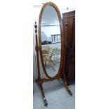 A modern Flemish design walnut framed cheval mirror, the oval plate pivoting on horns,