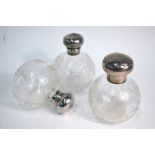 An Edwardian pair of finely-cut globular glass scent bottles with floral decoration and hinged bun