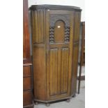 A carved oak hall cupboard with linenfold panelled door enclosing a fitted shelf and hanging rail