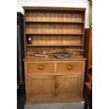 A waxed pine kitchen dresser, the plate rack with three open shelves over two drawers and panelled