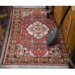 A Persian Hamadan rug with central floral  medallion on red ground with small rosettes within