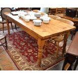 A stained pine kitchen dining table with rectangular top raised on turned legs